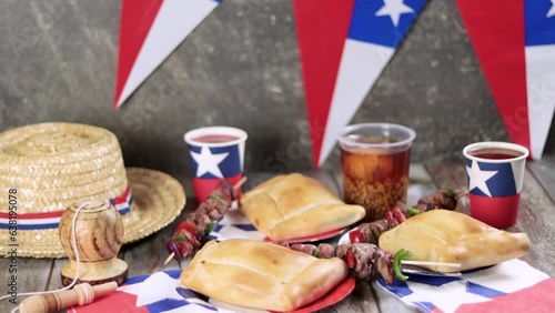 Fiestas Patrias Chile September 18, Independence Day. Empanadas, Anticuchos, mote con huesillo, chicha or wine, Sombrero, huaso, chupallas, straw and emboque, on a wooden table with flag and balloons photo