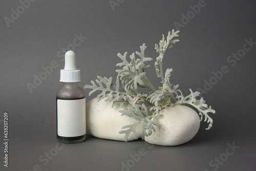 Cosmetic product, stones and silver leaves on dark grey background