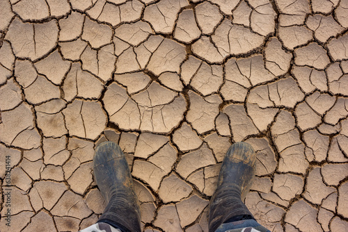 Walking in rubber boots on dry and sun-cracked silt