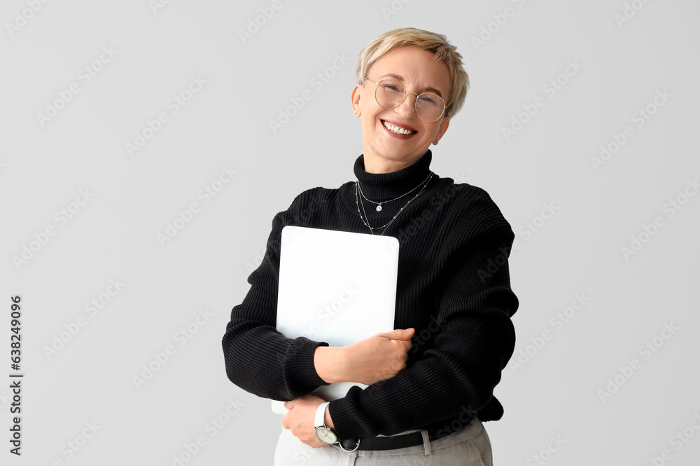 Beautiful mature woman with laptop on light background Beautiful mature woman with laptop on light background
