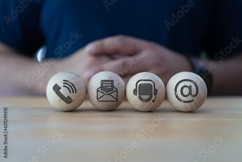 Contact us signs on wood ball spheres and human background. Contact us concept on website page. Customer support hotline and people connection
