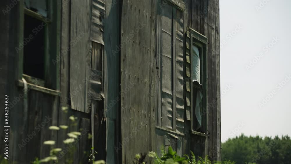 Wind blows quickly, broken open window and cloth curtain of ramshackle wooden building