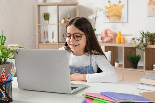 Little girl with laptop doi...