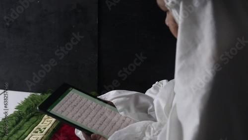 Muslim girl reading electronic Quran on tablet
 photo