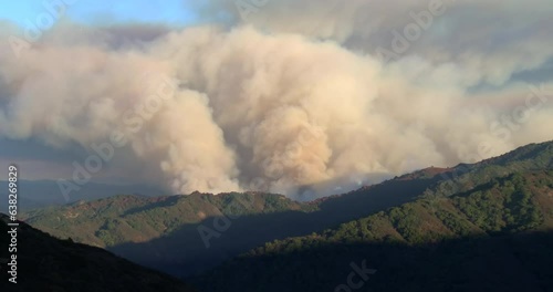 Slow zoom in on the Loma Fire wildfire burning in Santa Cruz Mountains above San Jose with massive smoke plume in late afternoon