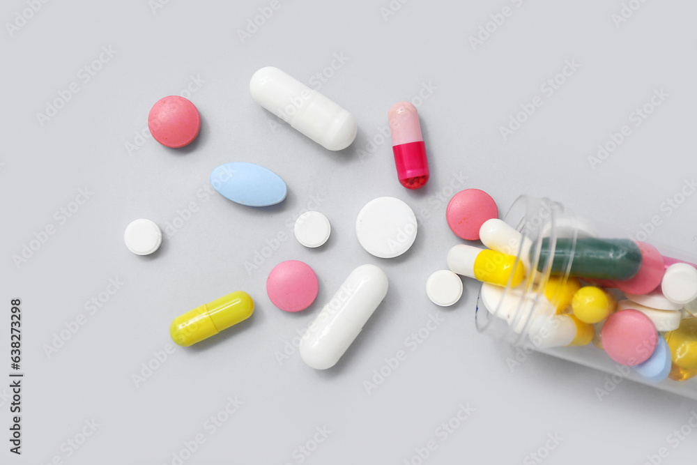Overturned bottle with different pills on grey background, closeup Overturned bottle with different pills on grey background, closeup