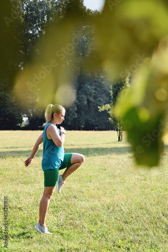 Active young woman jogging and practice training in a park outdoors. Athletic girl full of energy in sportswear with healthy body. Vertical.