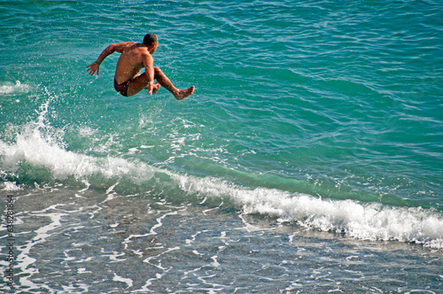 Amalfi, Amalfi Coast, Salerno, Campania, Italy, Europe - happy young man jumping to waters of Adriatic sea  after fast run on the beach, March