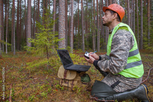 Forest engineer works in the forest with a computer. Digital technologies in the forest industry. The forest taxman works in the forest.