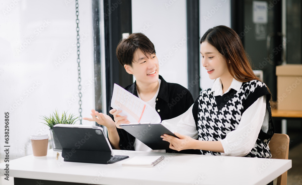 Asian business colleague business presents and explains and using laptop and tablet. Teamwork, financial marketing team, while sitting in modern office room.. Asian business colleague business presents and explains and using laptop and tablet. Teamwork, financial marketing team, while sitting in modern office room..