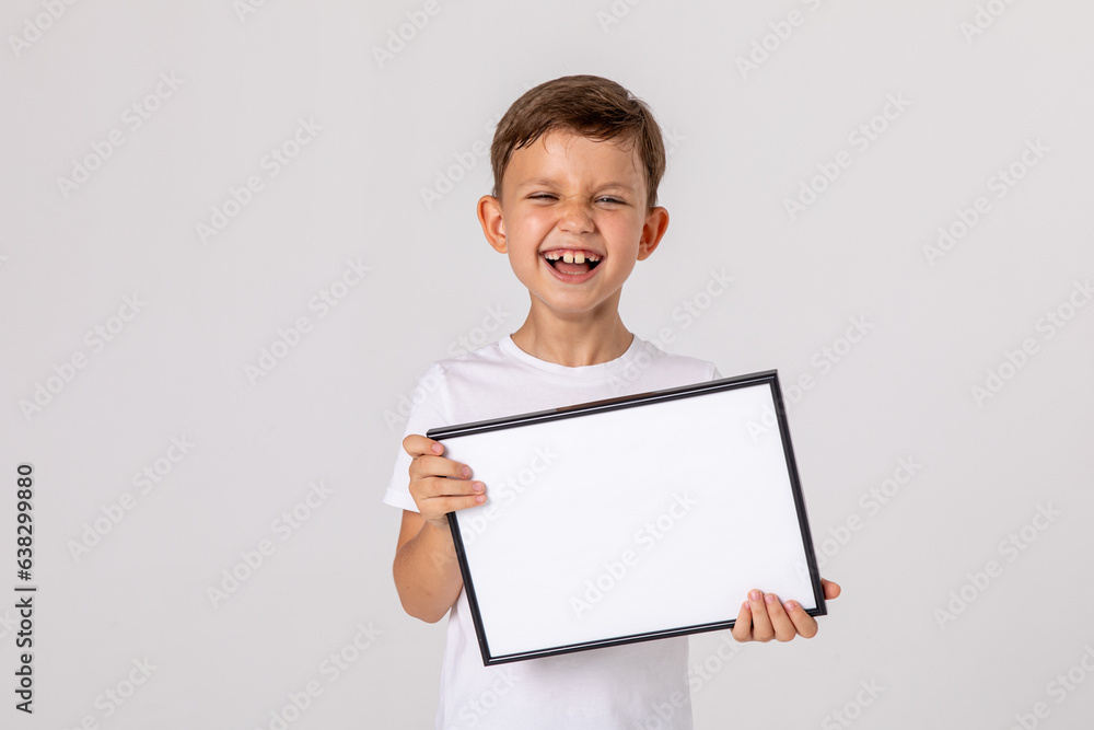 portrait of happy laughing baby boy holding white drawing Board on white background, young boy is holding a drawing board in her hands. white isolated background. Mock up. Copyspace. portrait of happy laughing baby boy holding white drawing Board on white background, young boy is holding a drawing board in her hands. white isolated background. Mock up. Copyspace.