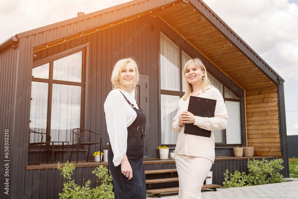 Blonde realtor talking to woman ready to buy summer house for elderly parents. Potential customer and real estate agent looking at camera, sunlight Blonde realtor talking to woman ready to buy summer house for elderly parents. Potential customer and real estate agent looking at camera, sunlight