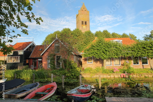 The bell tower of the church  in Jorwert, Friesland, Netherlands, a small village located 12km West from Leeuwarden, with historic houses and boats mooring in the foreground photo