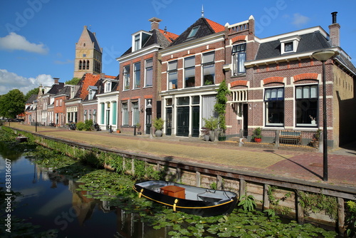 Obraz na płótnie Reflections of colorful house facades along Kleine Dijlakker street in Bolsward, Friesland, Netherlands, with the bell tower of Martinikerk (St Martin church) in the background w salonie
