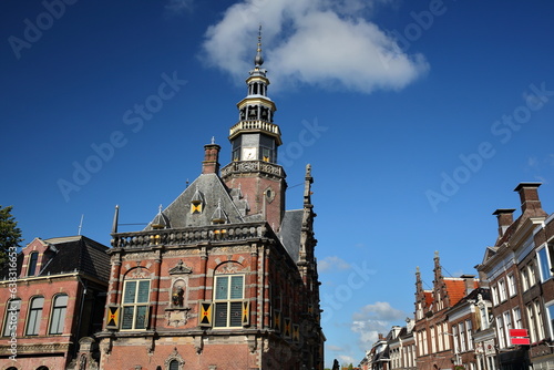 The ornate and colorful architecture of Renaissance style City Hall of Bolsward, Friesland, Netherlands, with historic house facades on the right