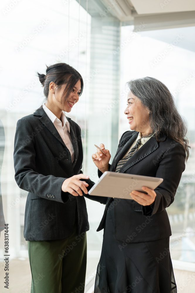 A professional senior Asian businesswoman is talking with a young colleague A professional senior Asian businesswoman is talking with a young colleague