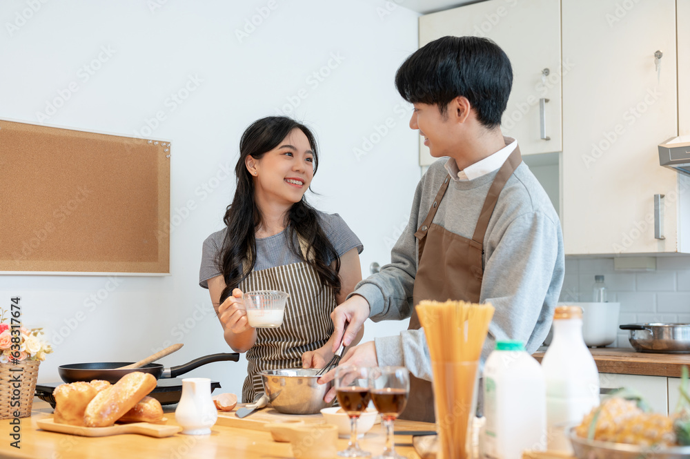 Fototapeta premium A joyful Asian couple enjoys baking pastry or making pancakes in the kitchen together.
