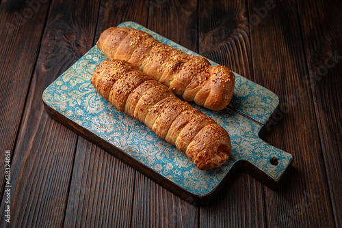 Sausage in dough, meat bun on brown boards. For decoration of bakery sales outlets. Bakery products. Fresh bakery.