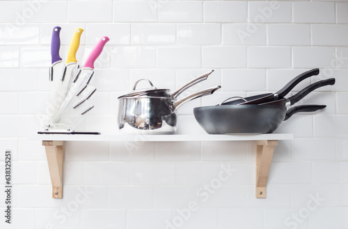 Modern design of white kitchen with knife collection and a pan, a pot on decor wall