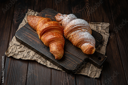 Delicate fluffy ruddy croissant with butter on brown boards. Bakery products. Fresh bakery.