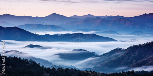 The mountains are shrouded in mist  and the last traces of daylight lend a tranquil  mystical quality to the scene. A twilight shot of autumn mountains under a fading pink and purple sky.