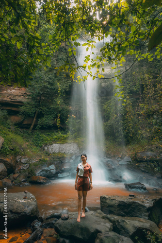 A young beautiful Asian girl explores a waterfall during her summer vacation in Laos  Asia