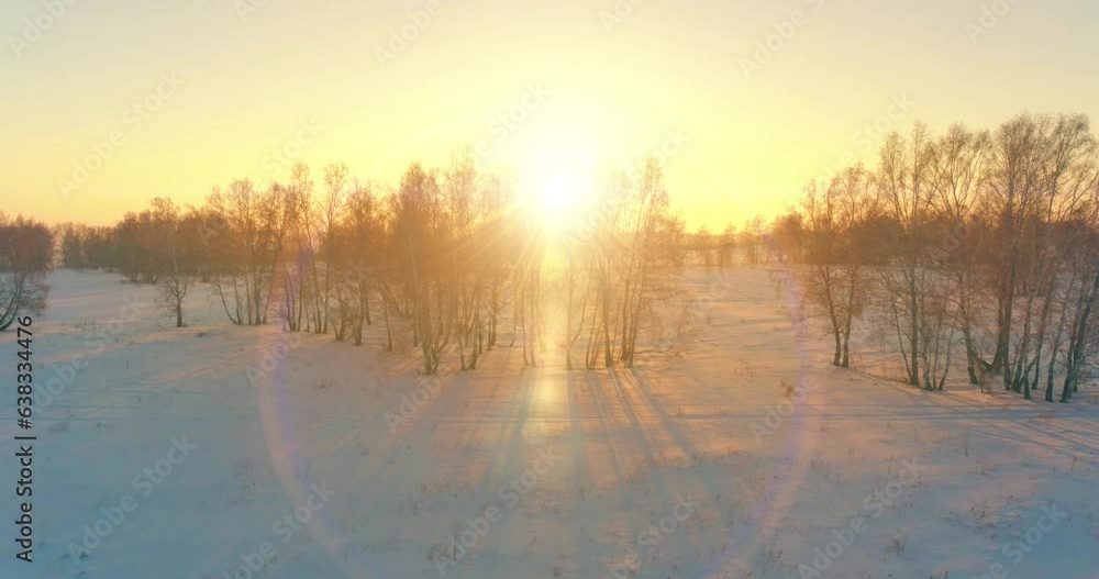 Aerial drone view of cold winter landscape with arctic field, trees covered with frost snow and morning sun rays over horizon. Extreme weather. Aerial drone view of cold winter landscape with arctic field, trees covered with frost snow and morning sun rays over horizon. Extreme weather.
