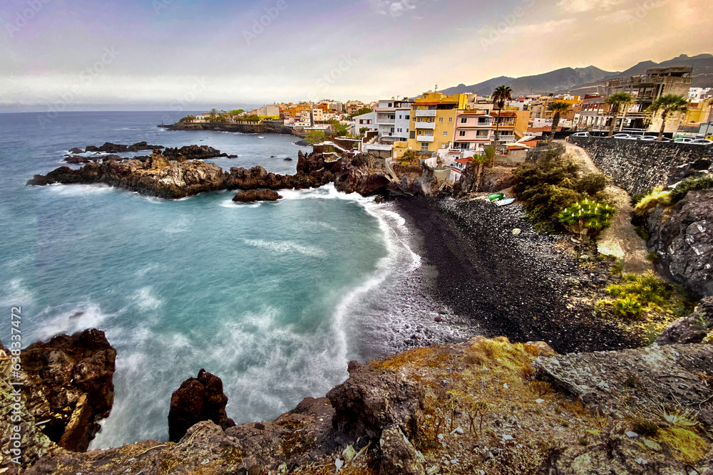 Fototapeta premium Exclusive beach of Tenerife. Beautiful sunset by the Atlantic Ocean. Epic volcanic rocks, cliffs, black sand, waves, turquoise water. Premium landscape from pure nature, town Alcalá, Canary Islands 