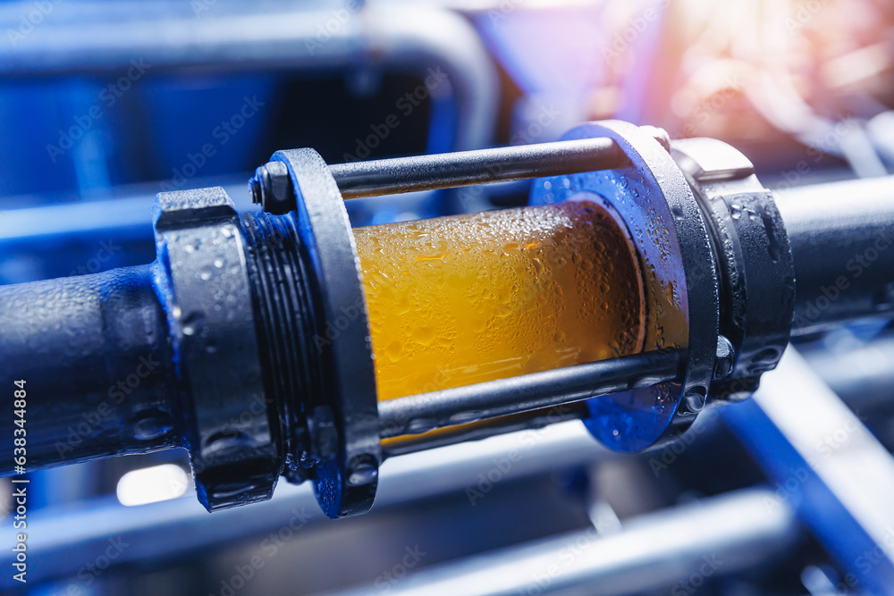Fototapeta premium Brewing equipment for quality control, sight glass full of golden beer on stainless steel pipe. Concept brewery industry