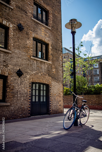 A bike resting on a lampost in London docks on a nice day.