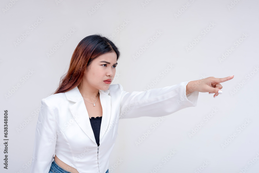 An irked and irritable young woman glaring and pointing to the right. Isolated on a white background. An irked and irritable young woman glaring and pointing to the right. Isolated on a white background.