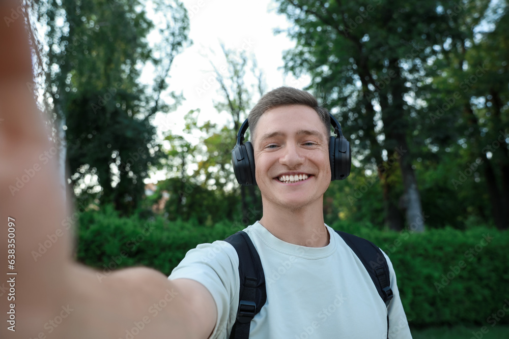 Smiling man in headphones taking selfie in park Smiling man in headphones taking selfie in park