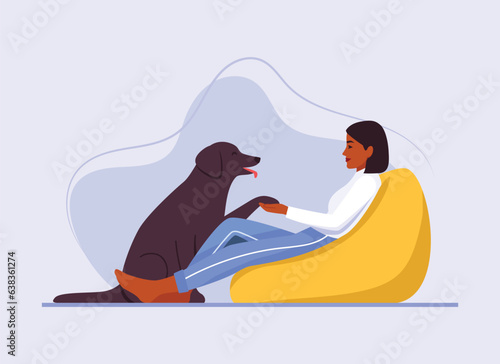 dark-skinned girl sits on a bean bag chair with a dog