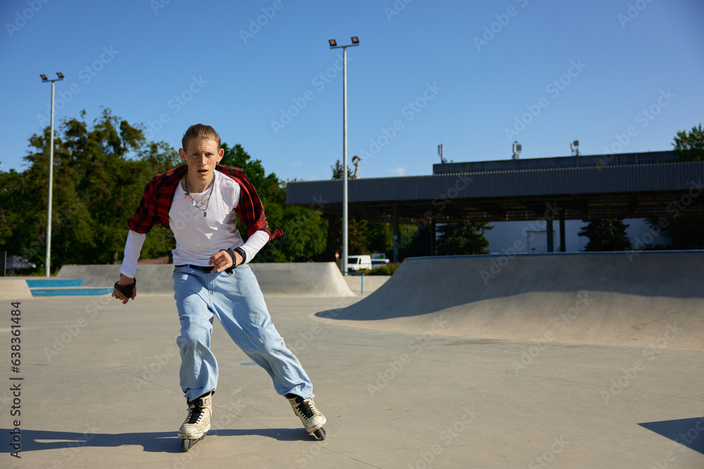 Obraz premium Trendy fashioned teenage guy rollerblading at urban skating park