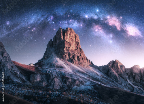 Milky Way acrh over beautifull rocks at starry night in autumn in Dolomites, Italy. Landscape with purple sky with stars and bright arched milky way over high alpine rocky mountains. Space. Nature