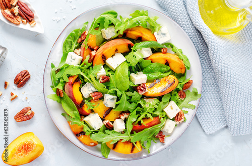 Grilled Peach Salad with Blue Cheese, Pecans and Arugula on Bright Light Blue Background