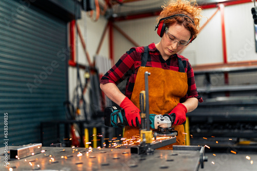 Canvastavla A young girl who is an apprentice in a metal workshop uses a grinder and works o