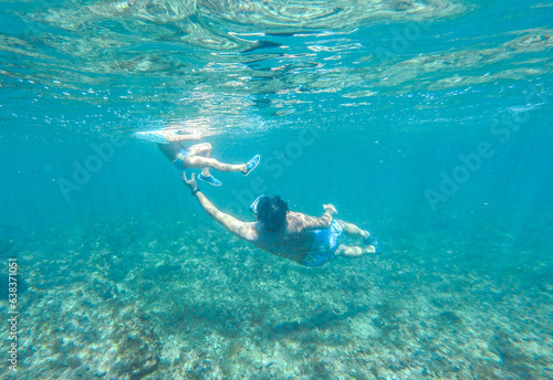 Father teaching his son to swim in the beautiful crystal blue water of the sea