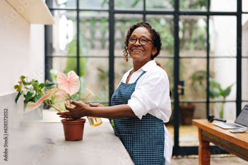 Принти на полотні Cheerful flower arranger taking care of a plant in her shop