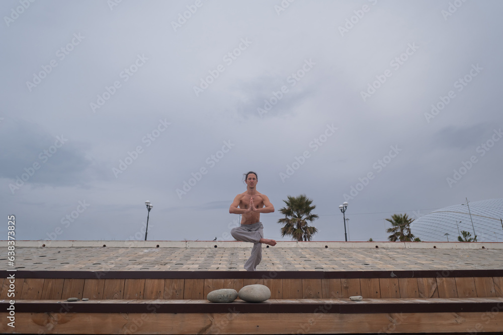 Obraz premium Caucasian man with naked torso practicing wushu on the seashore. 