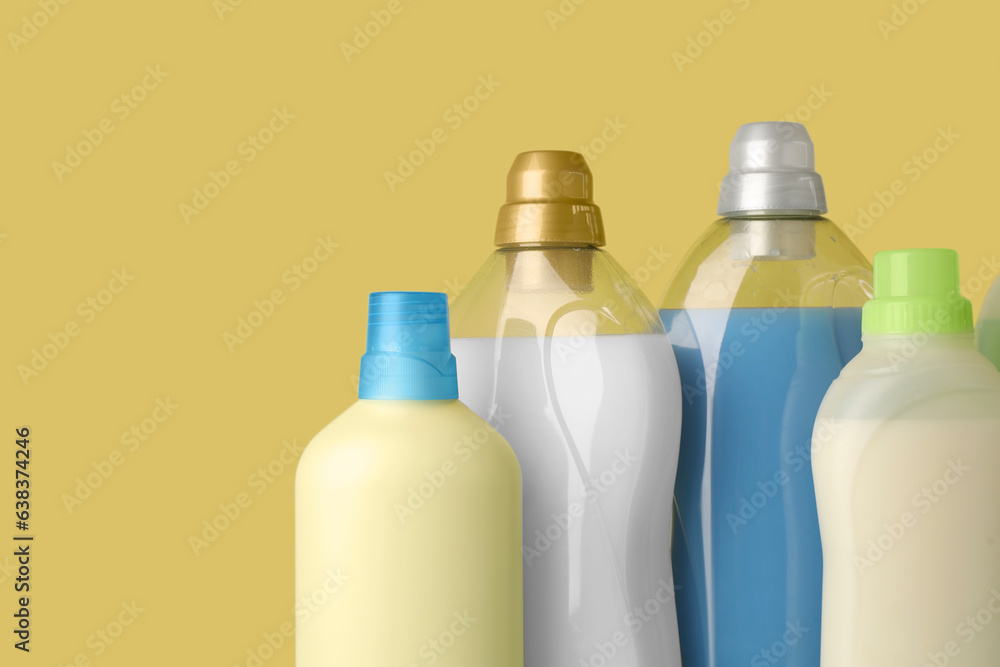 Bottles of fabric softener on yellow background, space for text Bottles of fabric softener on yellow background, space for text