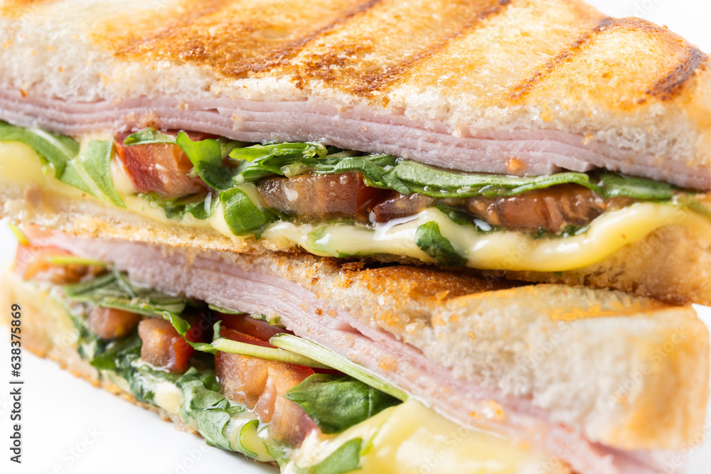 Fototapeta premium Panini sandwich with ham, cheese, tomato and arugula. Close up