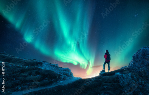 Northern lights and young woman on mountain peak at night. Auror
