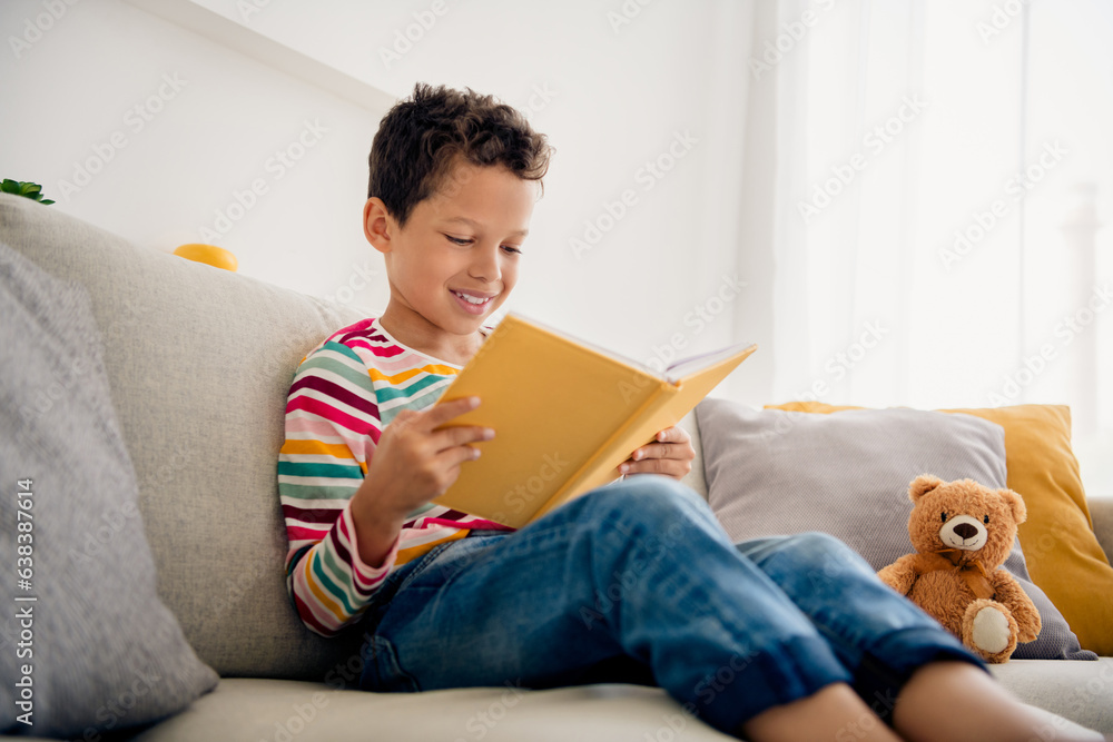 Portrait of reading magazine small schoolboy cute spending free time copybook photo memories album lying grey couch isolated home interior Portrait of reading magazine small schoolboy cute spending free time copybook photo memories album lying grey couch isolated home interior