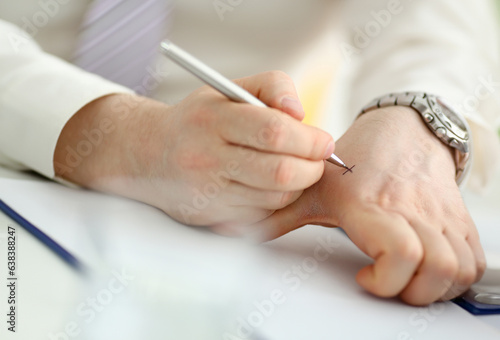 Male make x cross note with silver pen at his arm for keep in mind in office closeup. Try not to forget to do list concept