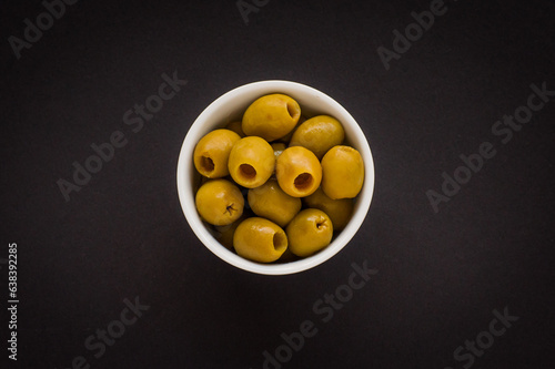 Принти на полотні Green olives in a white bowl on a black background