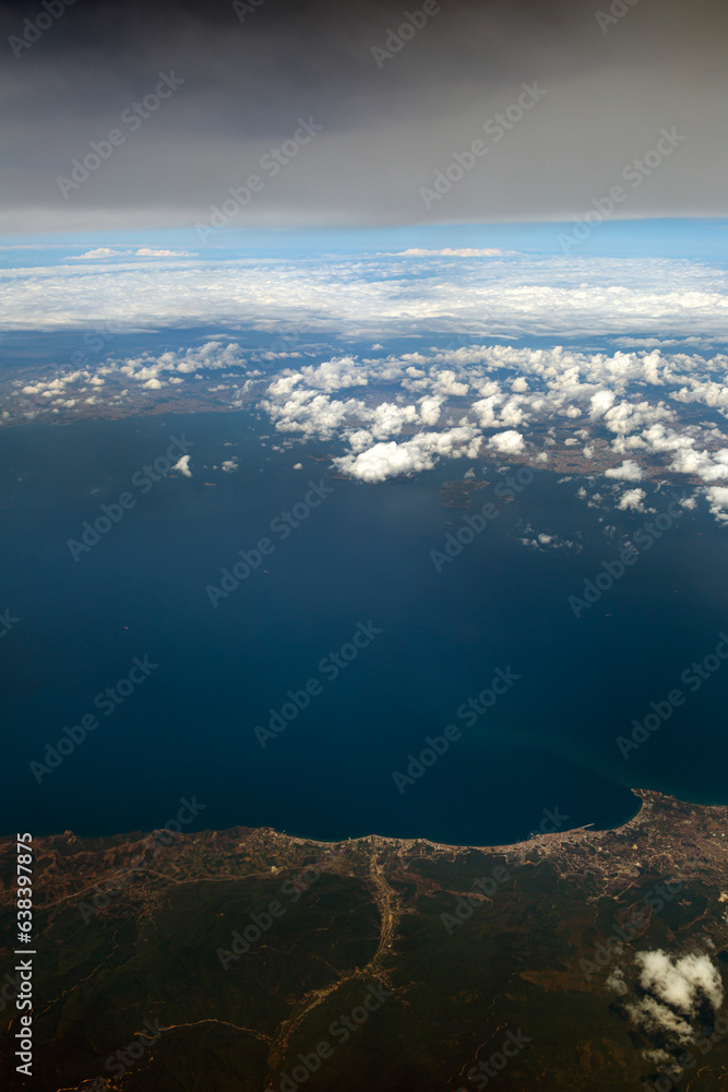 aerial view from the window of airplane with white clouds and shadows on the earth 