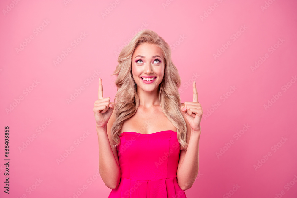 Photo of positive excited girl dressed sexy outfit looking pointing two fingers up empty space isolated pink color background Photo of positive excited girl dressed sexy outfit looking pointing two fingers up empty space isolated pink color background
