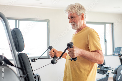 Athletic white-haired senior man doing exercises in gym area to stay fit. Sport, gym, wellbeing concept