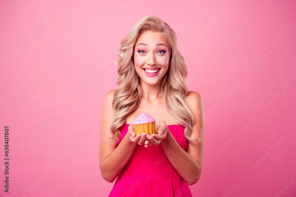 Portrait of adorable cheerful girl toothy smile hands hold little tasty cake muffin isolated on pink color background Portrait of adorable cheerful girl toothy smile hands hold little tasty cake muffin isolated on pink color background